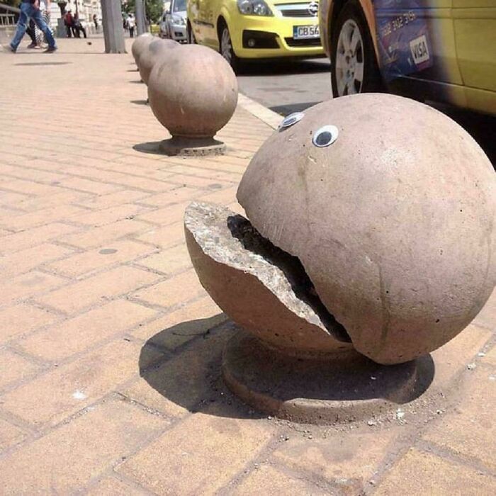Concrete street art bollards designed as c*****d spheres with eyes, creating a playful and powerful urban street art display.