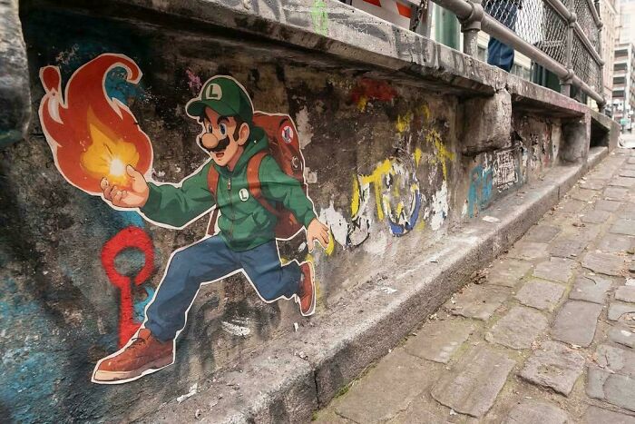 Street art of a character in green running with a fiery ball on a worn urban stone wall along a cobblestone street.