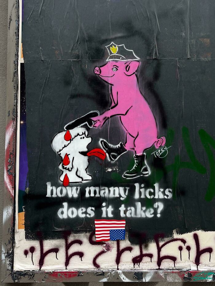 Street art of a pink pig in boots holding a baton over a dog with blood, highlighting powerful street art and social commentary.