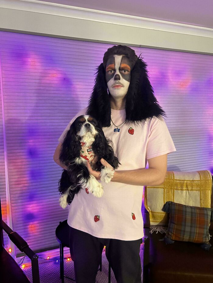 Person wearing a creative Halloween costume with dog face paint and holding a dog, showcasing unique Halloween costume ideas.