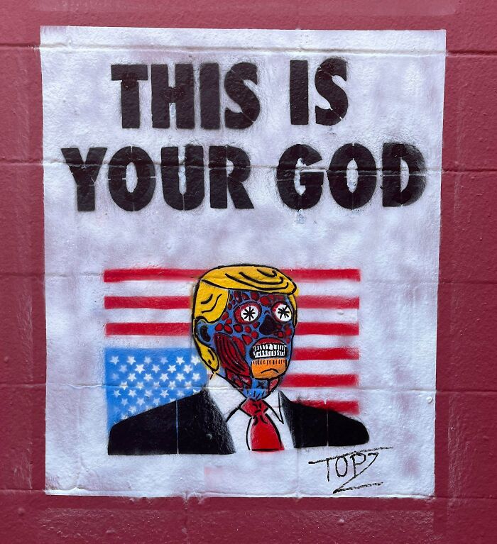 Street art of a figure resembling a politician with a vibrant skeletal face and an American flag background on a red wall.