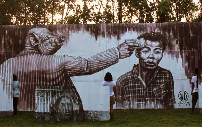 Powerful street art mural depicting a pig-headed figure holding money to a man's head, illustrating corruption and societal issues.