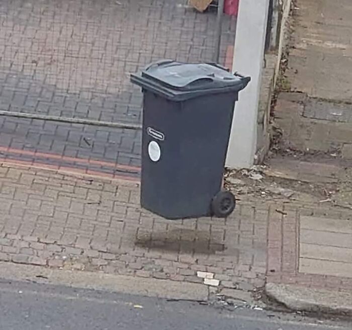 Unphotoshopped photo of a trash bin appearing to float above the ground, creating a freaks me out effect.