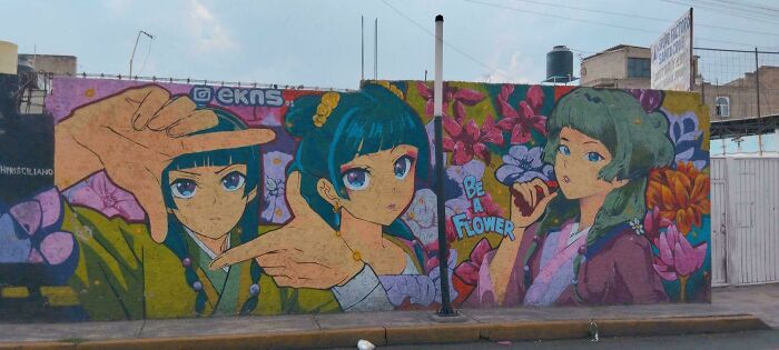 Colorful street art mural featuring three anime-style characters surrounded by vibrant flowers in an urban setting.
