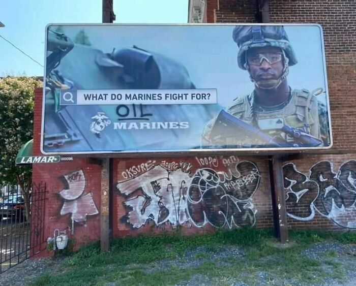 Billboard featuring Marines juxtaposed with vibrant graffiti art, showcasing powerful street art from urban surroundings worldwide.