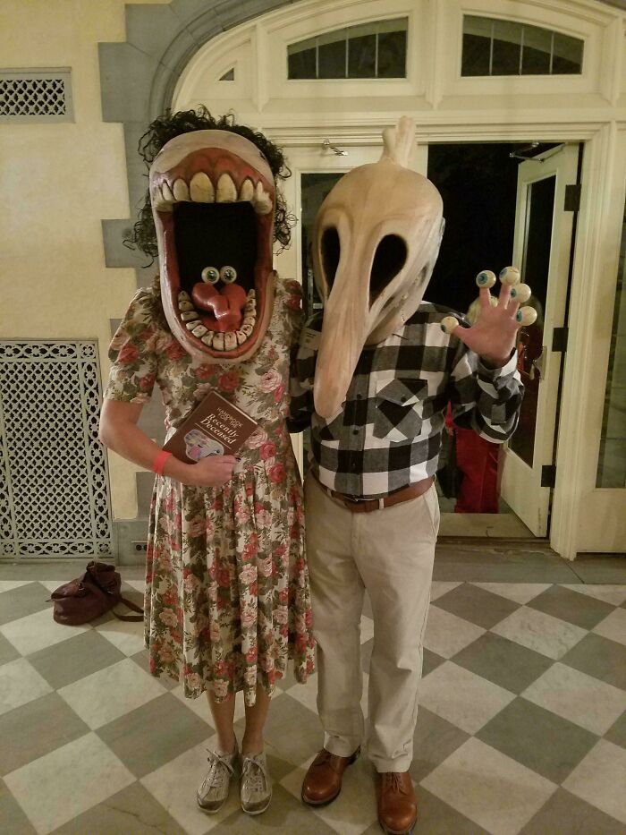 Two people wearing creative Halloween costume ideas, including a large mouth mask and a bird-like mask with eyeballs on fingers.