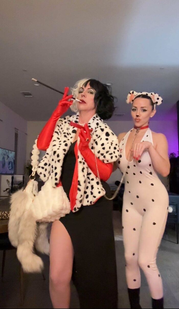 Two women in genius Halloween costumes inspired by dalmatians, featuring spotted patterns and themed accessories indoors.