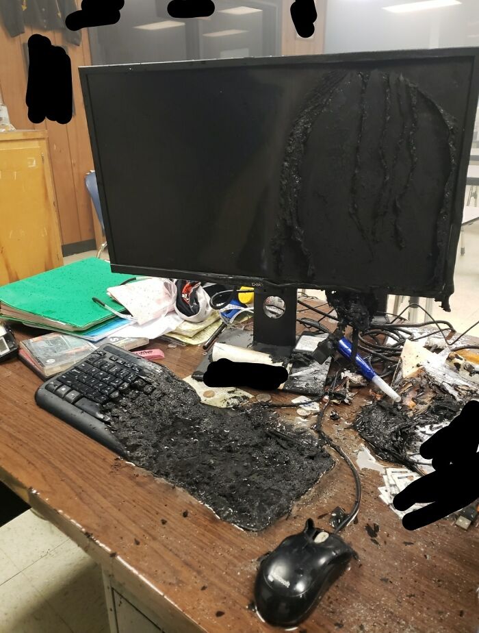 Burned computer monitor and melted keyboard on cluttered desk, illustrating painful electronics handling mistakes.
