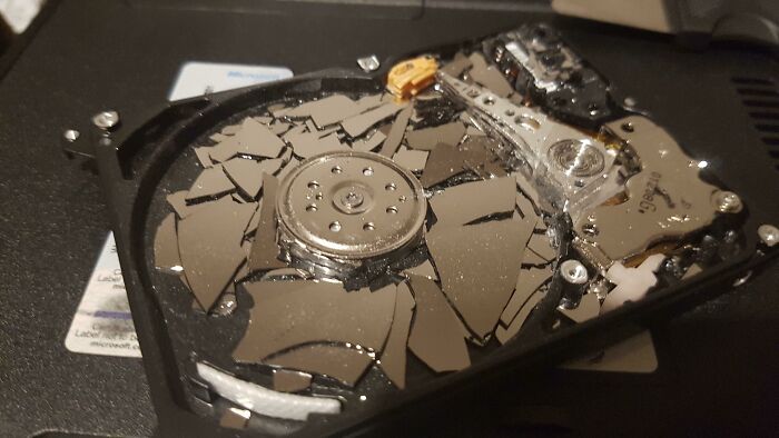 Broken hard drive with shattered platters inside, showing a painful example of handling electronics the wrong way.