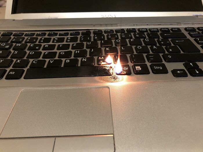 Flame burning a laptop keyboard, illustrating a painful electronics handling mistake and soldering gone wrong.
