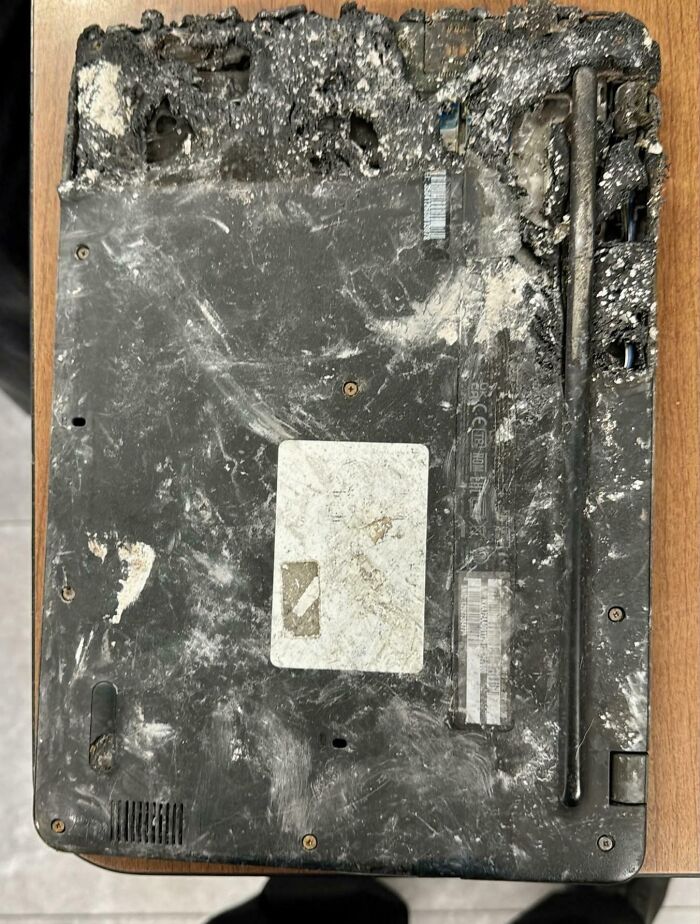Heavily damaged and burnt laptop bottom case showing extreme misuse of electronics and failed soldering attempts.