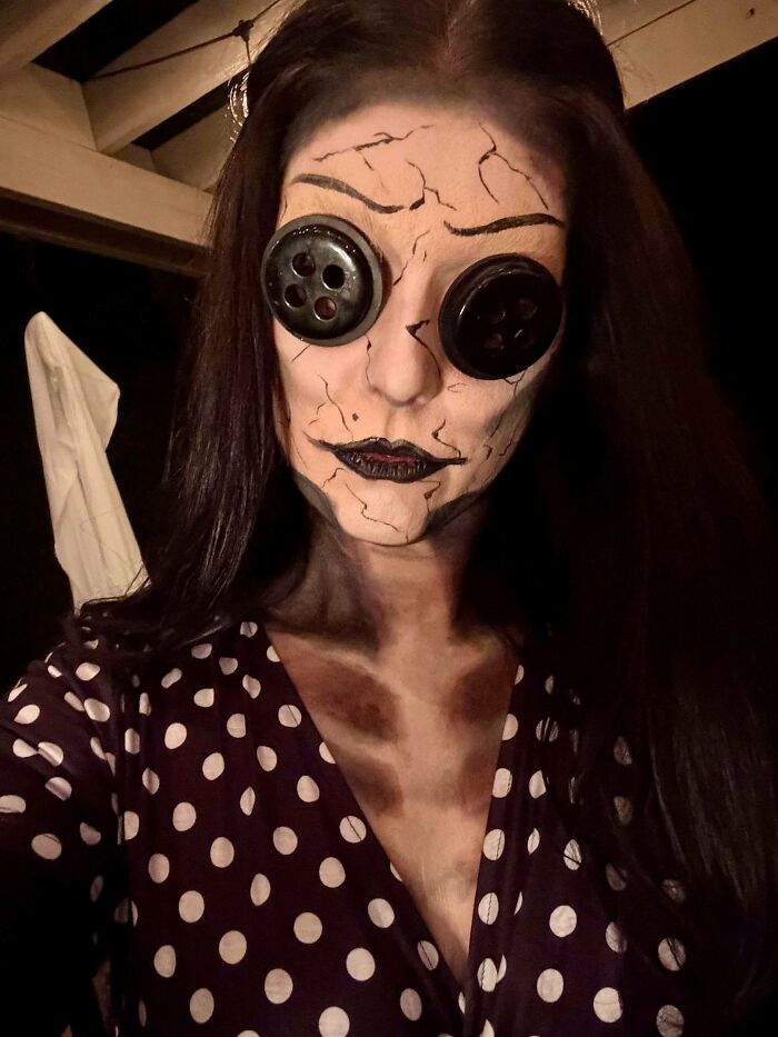 Woman wearing a creative Halloween costume with c*****d face makeup and large button eyes for Halloween costume ideas.