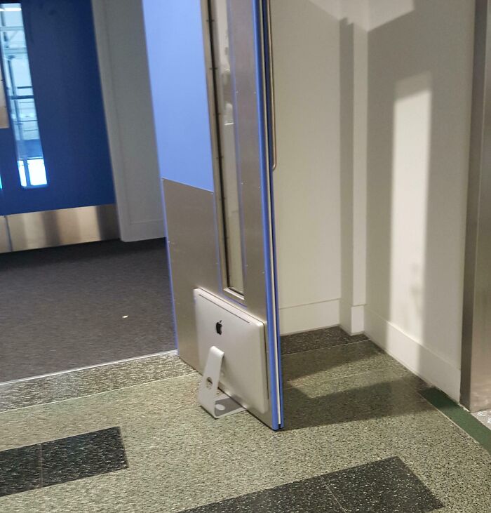 iMac used as a makeshift doorstop, showing incorrect handling of electronics in a creative but damaging way.