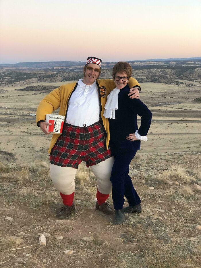 Two people posing outdoors in creative Halloween costume ideas featuring a humorous outfit and a vintage-style suit.