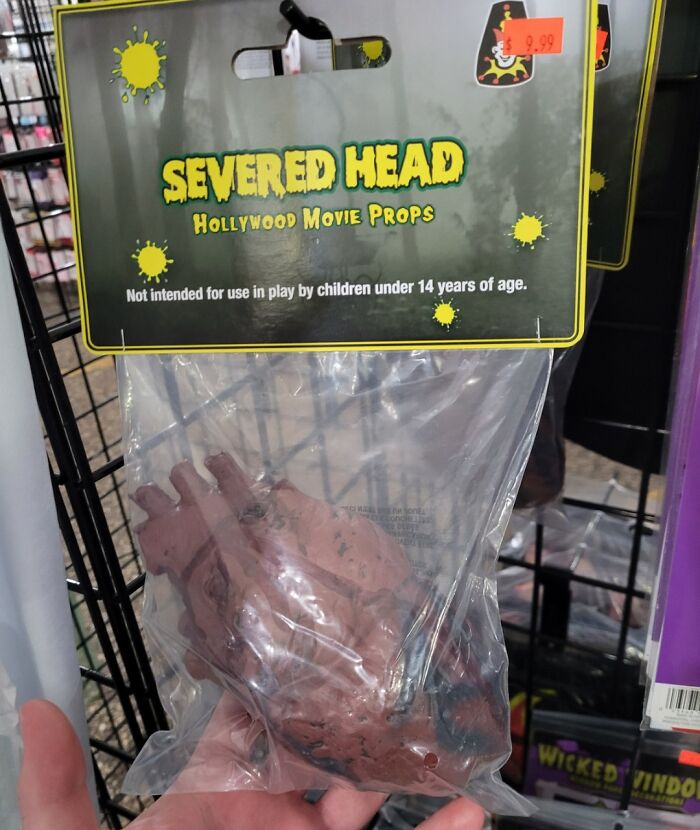 Severed head Halloween prop in packaging displayed as a funny off-brand Halloween costume accessory for decoration.