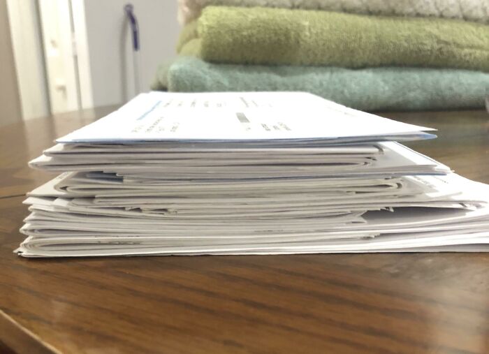 Stack of medical bills on a wooden table highlighting the harsh realities of American healthcare costs and paperwork.