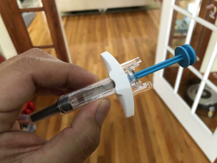 Hand holding a medical syringe with clear liquid, highlighting the harsh realities of American healthcare costs.