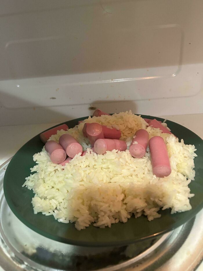 Plate of plain white rice topped with sliced sausages appearing unappetizing in unholy food pics.
