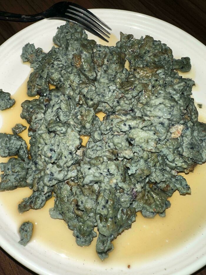 Plate of unholy food with an unappetizing grayish texture and oily residue, showcasing bizarre and unpleasant food pics.