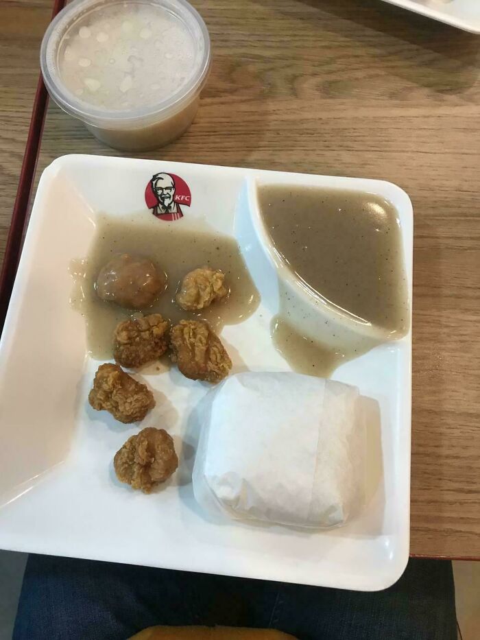 KFC meal with small dry chicken pieces and gray gravy, an unholy food pic that looks unappetizing on a white tray.
