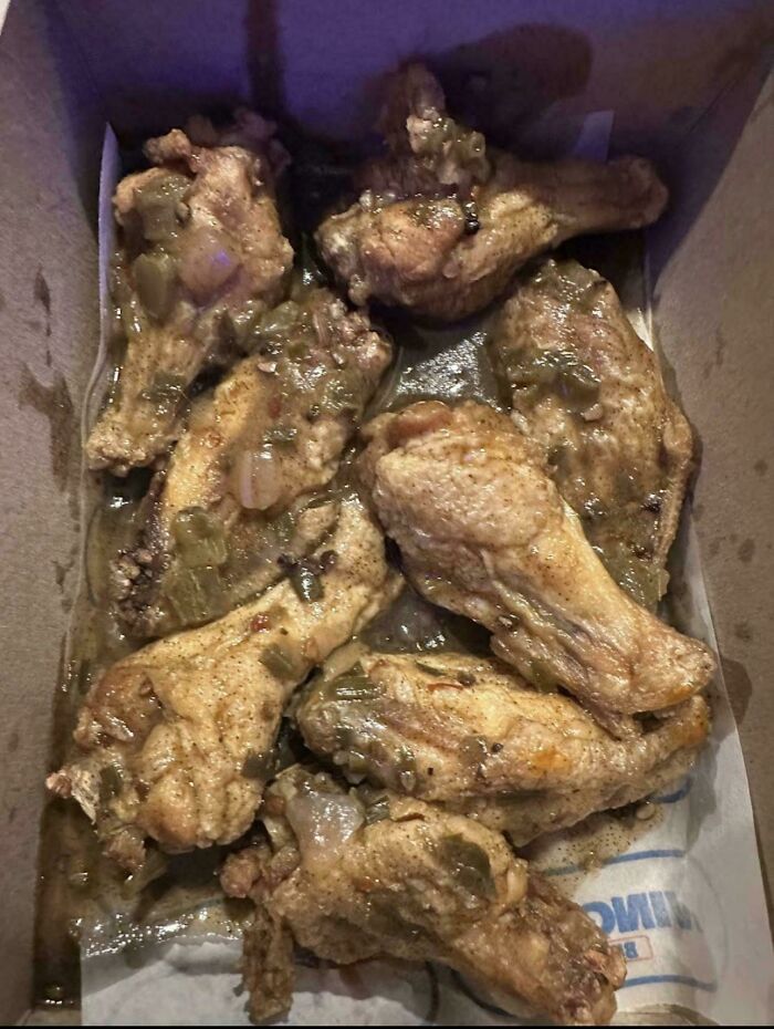 Unappetizing chicken wings covered in an unappealing sauce in a takeout box, an unholy food pic example.