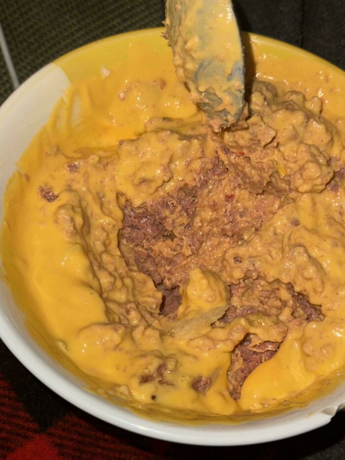 Bowl of unholy food with a lumpy, unclear mixture covered in thick, yellow cheese sauce—unappetizing food pics.
