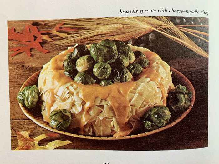 Brussels sprouts with cheese and noodle ring plated on a wooden surface, an unholy food pic that looks unappetizing.