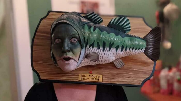 Person wearing a creative Halloween costume with a mounted fish headpiece inspired by the Big Mouth Billy Bass toy.