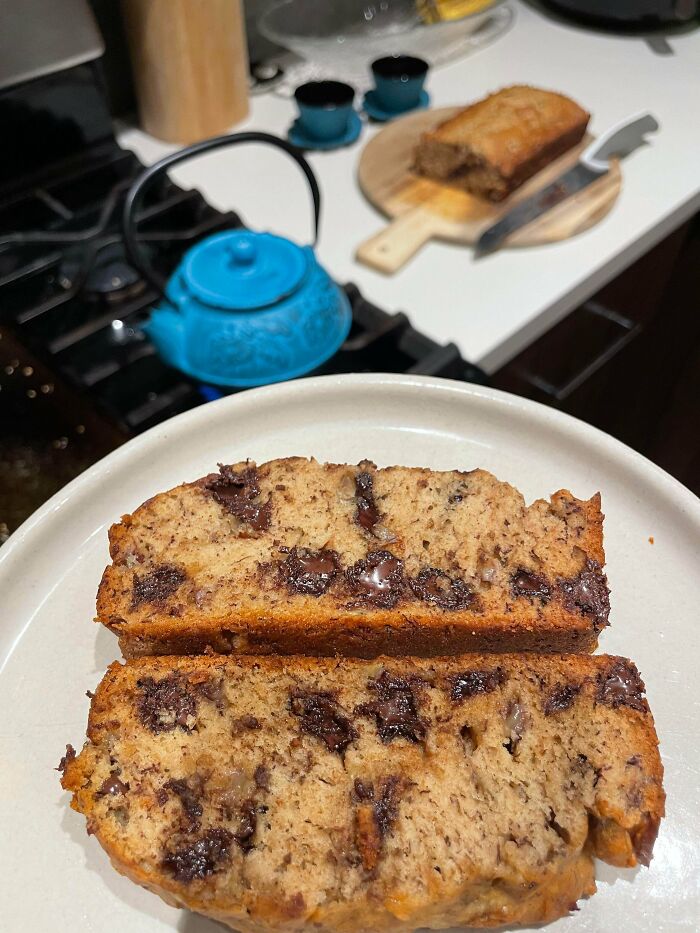 Two slices of homemade chocolate chip banana bread on a white plate in a kitchen, reflecting simple living.