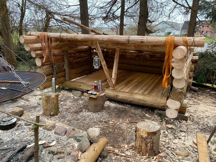 Simple living shelter made of logs in a natural setting, showcasing minimalist outdoor lifestyle and having less essentials.