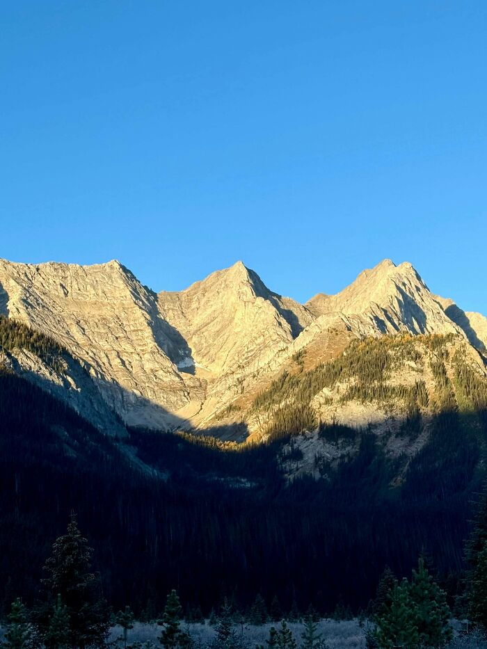 Mountain peaks illuminated by sunlight against a clear blue sky, reflecting the peace of simple living outdoors.