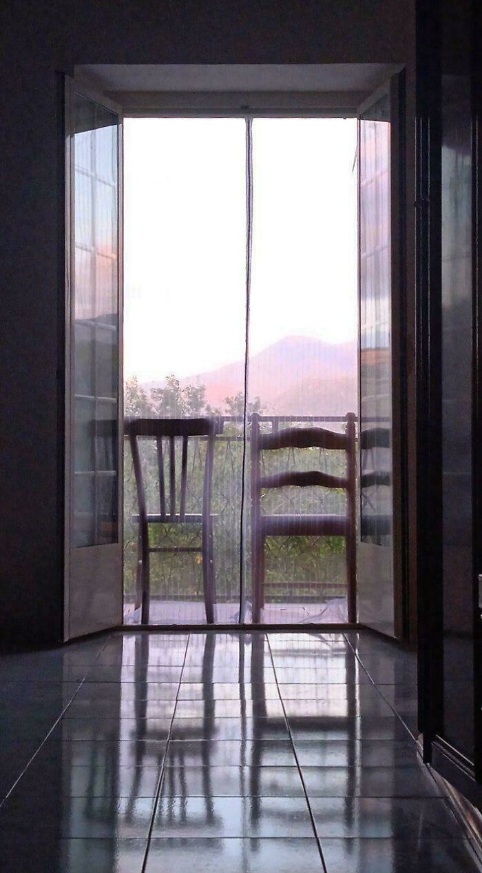 Two simple wooden chairs on a balcony with natural light and a peaceful view, reflecting simple living lifestyle.