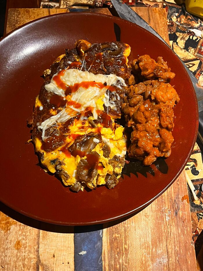 Plate with simple living meal of eggs with sauce and a side of beans on a wooden table background.