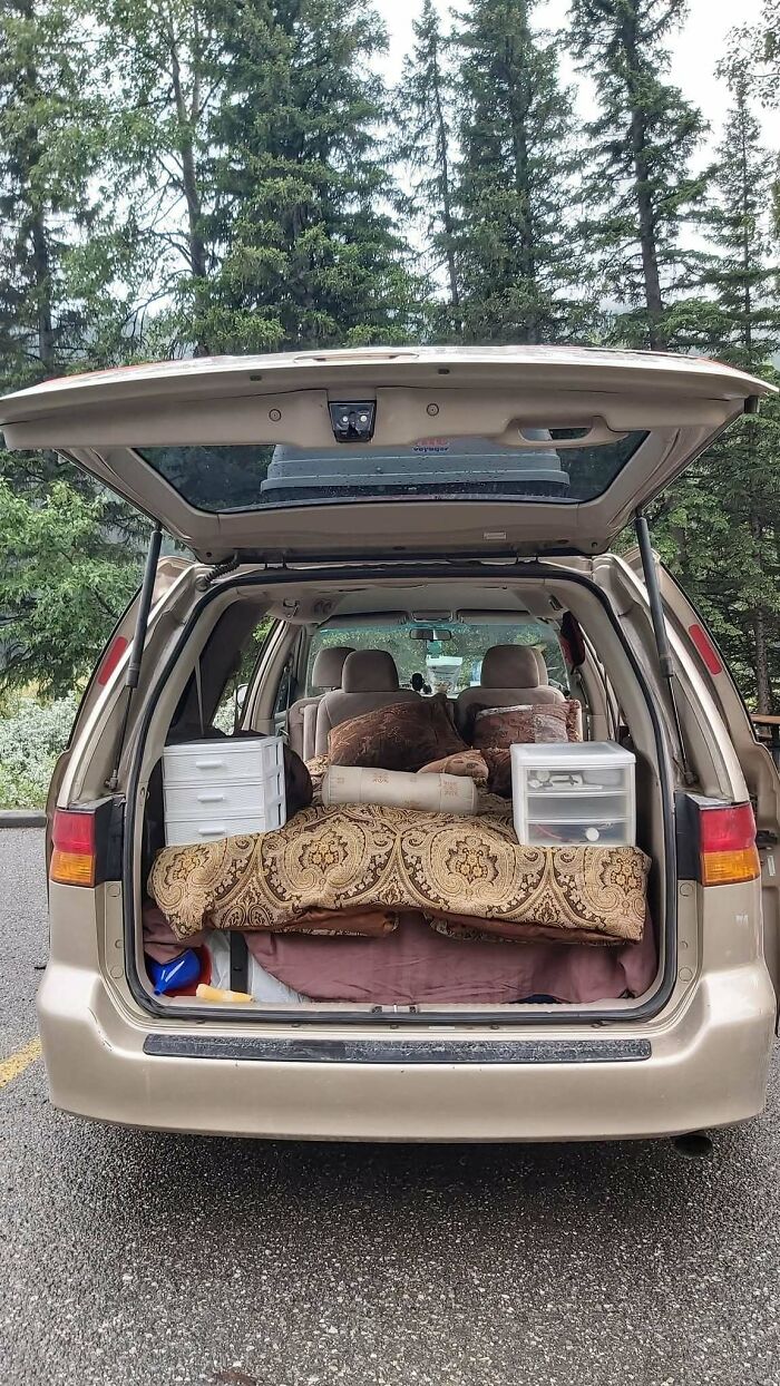 Open van packed minimally with bedding and storage bins, illustrating simple living and appreciating having less outdoors.