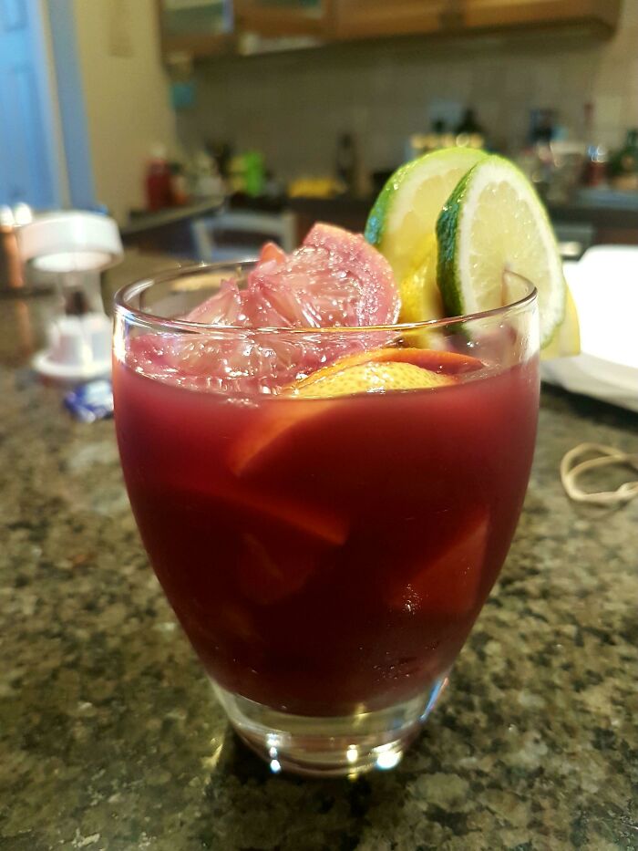 Glass of red beverage with ice and citrus slices on a kitchen counter showcasing foods not popular in their country