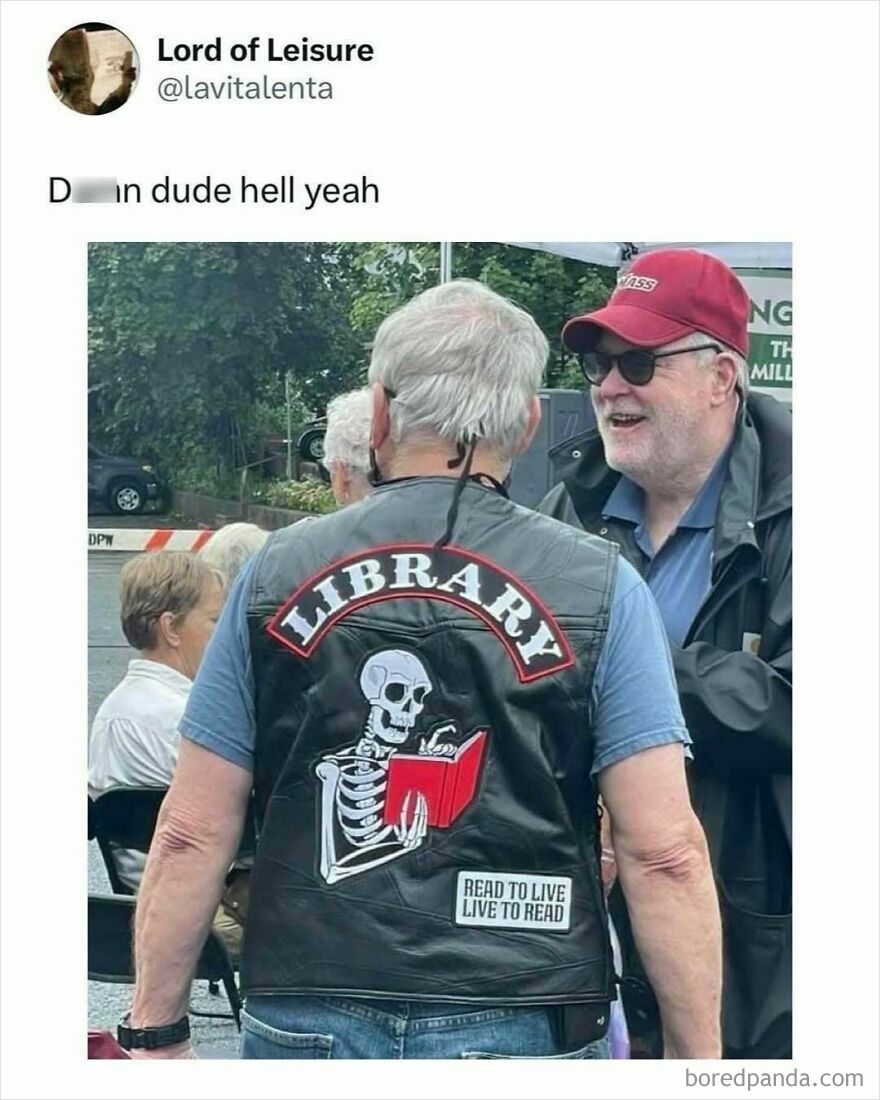 Older man wearing a leather vest with a skeleton holding a book and the word library, a funny dad meme about reading.