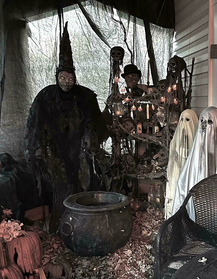 Outdoor Halloween decorations with spooky witches, ghosts, skeletons, and a cauldron creating a haunted scene on a porch.