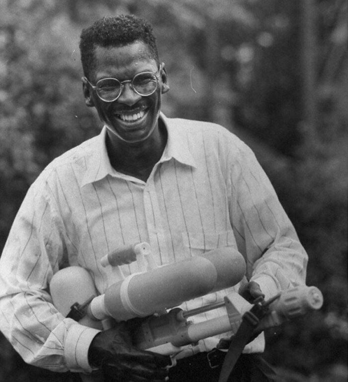 Smiling man in glasses holding a homemade water gun, a fascinating photo offering a unique view of the world.