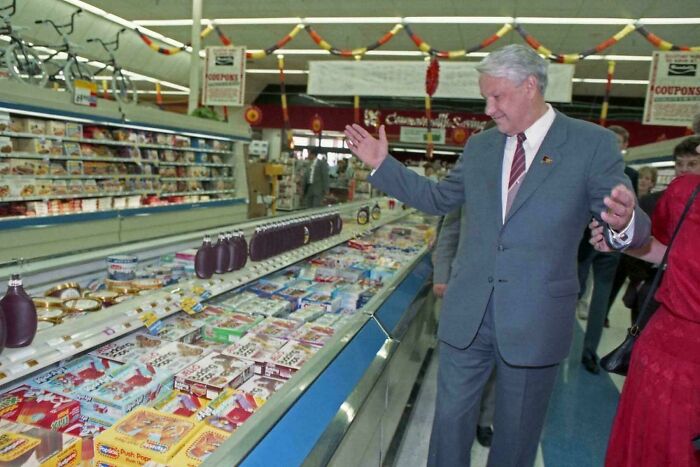Man in a suit exploring a supermarket aisle filled with various packaged goods, showcasing fascinating photos and facts.