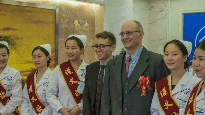 Group photo of nurses and two men in suits wearing red sashes, showcasing fascinating photos that may help you see the world differently