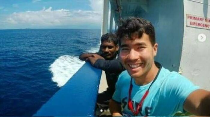 Two men smiling on a boat at sea with clear blue water, captured in a fascinating photo showing a unique moment.