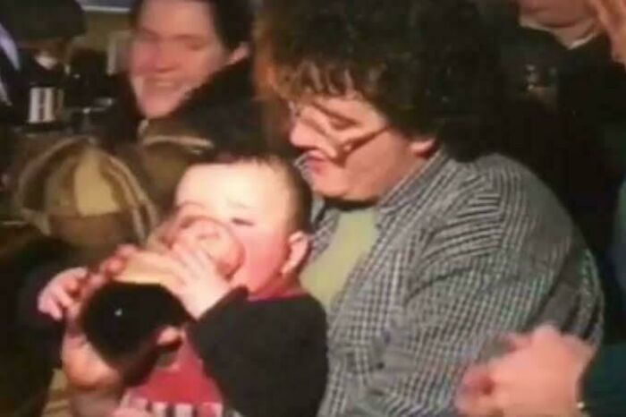 Baby held by an adult pretending to drink from a bottle, a fascinating photo that may help you see the world differently.