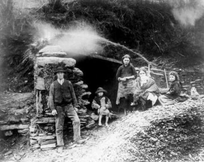Black and white photo showing a family outside a stone shelter, part of fascinating photos revealing stories that change perspectives.