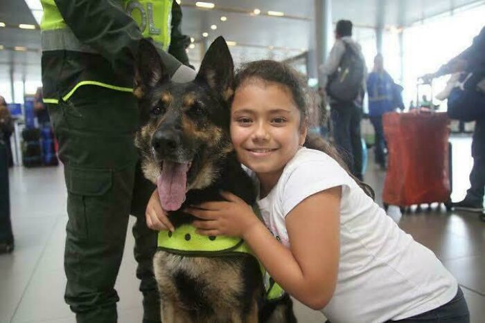Young girl hugging a police dog with officers in the background showing fascinating photos and stories of the world.
