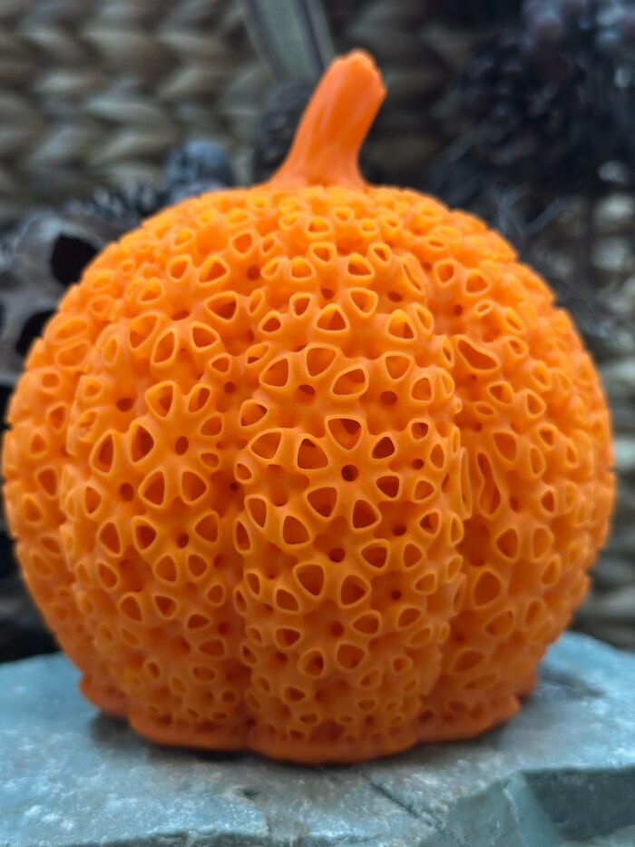 Close-up of an orange pumpkin-like object with numerous small holes, triggering trypophobia discomfort.
