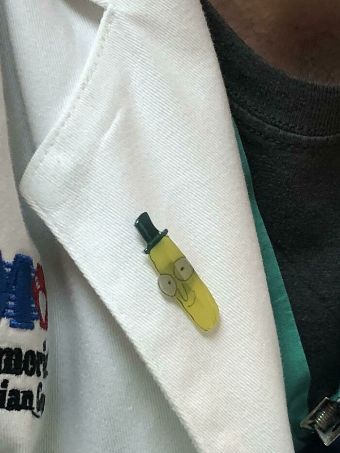 Close-up of a doctor’s white coat with a quirky Pickle Rick pin to put patients at ease and lighten the mood.