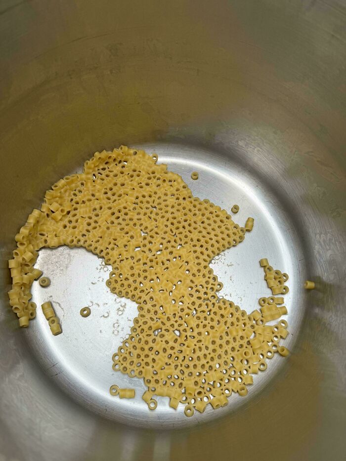 Close-up of pasta pieces clustered inside a metal pot, showing a pattern that may trigger trypophobia discomfort.