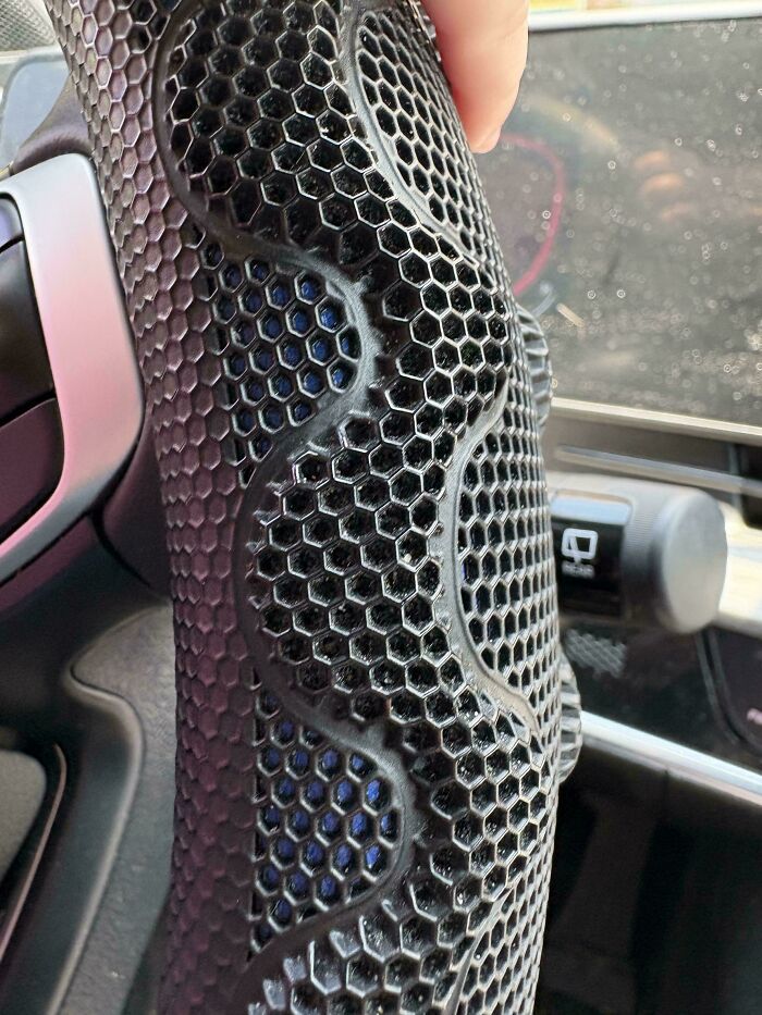 Close-up of a black honeycomb pattern on a car accessory, a trypophobia trigger with hexagonal holes and texture.