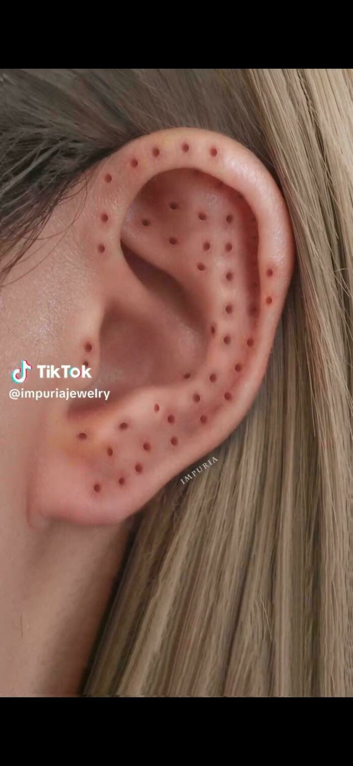 Close-up of a human ear covered with multiple small holes, triggering trypophobia discomfort and reaction.