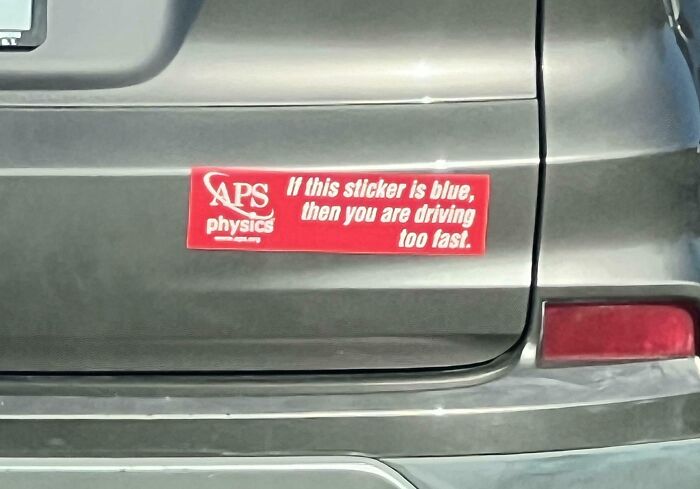 Red bumper sticker on gray car with a clever physics joke about driving speed and sticker color on the road.